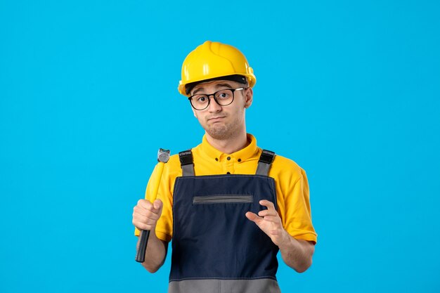 Männlicher Baumeister der Vorderansicht in Uniform und Helm mit Hammer auf Blau