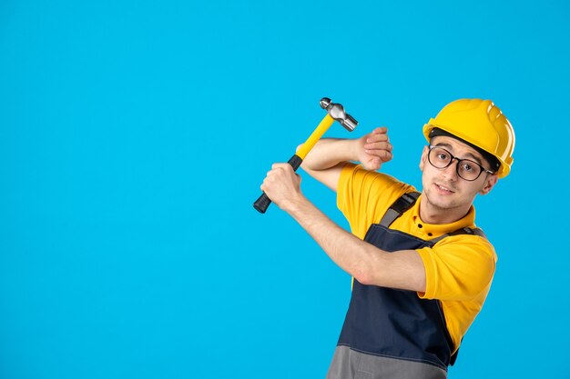 Männlicher Baumeister der Vorderansicht in Uniform und Helm mit Hammer auf Blau