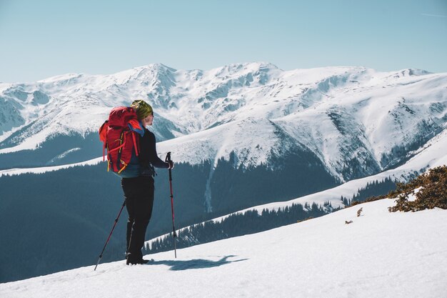 Männlicher Bergsteiger, der den schneebedeckten Bergblick vom Gipfel genießt