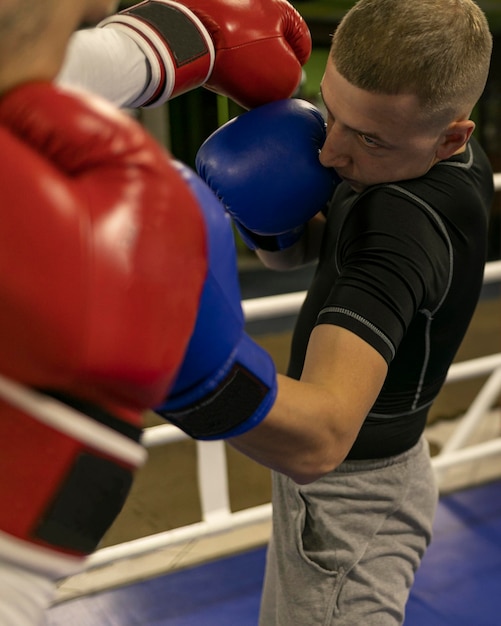 Männlicher Boxer, der im Ring mit Trainer übt