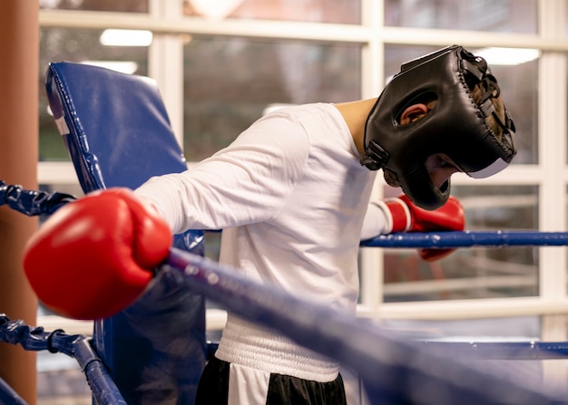 Männlicher Boxer mit Helm und Handschuhen im Ring