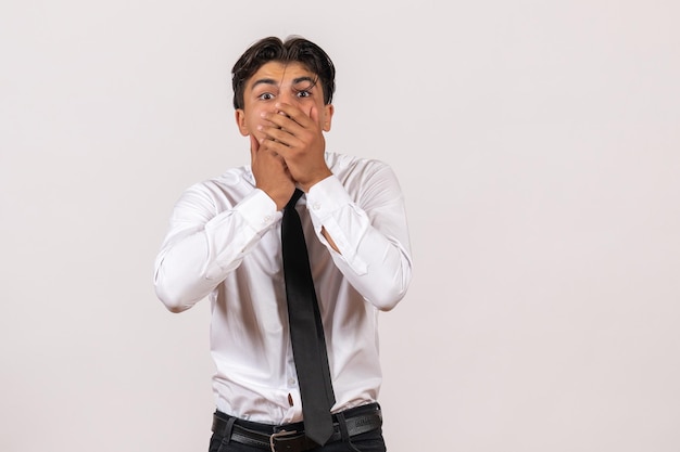 Männlicher Büroangestellter der Vorderansicht mit schockiertem Gesicht auf einer weißen Wand, der männliches Jobgeschäft arbeitet