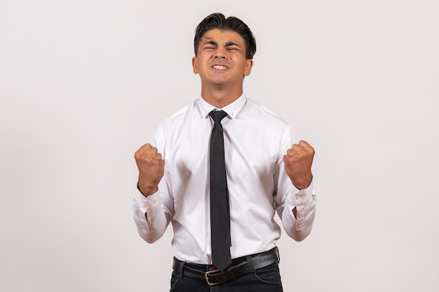 Männlicher Büroangestellter der Vorderansicht mit starken Emotionen auf der weißen Wand arbeitet männliches Jobgeschäft