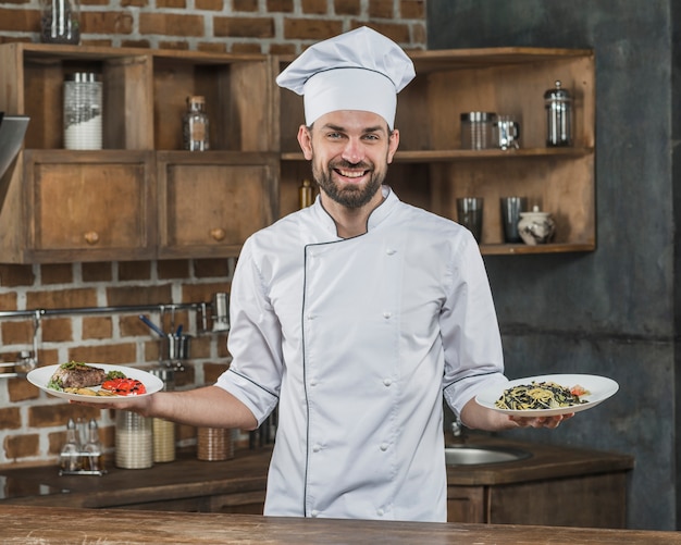 Männlicher Chef, der köstliche Teller in der Küche darstellt