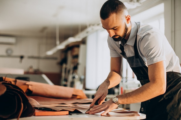 Männlicher Designer und Lederschneider, der in einer Fabrik arbeitet