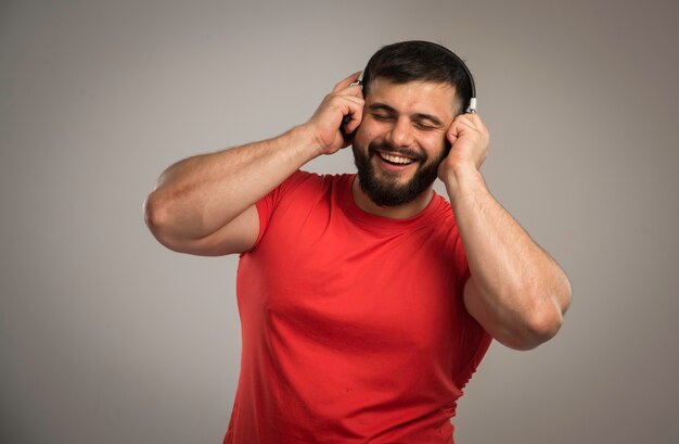 Männlicher DJ im roten Hemd, das Kopfhörer trägt.
