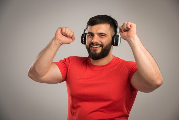 Männlicher DJ im roten Hemd, der Kopfhörer trägt und Musik beim Tanzen hört