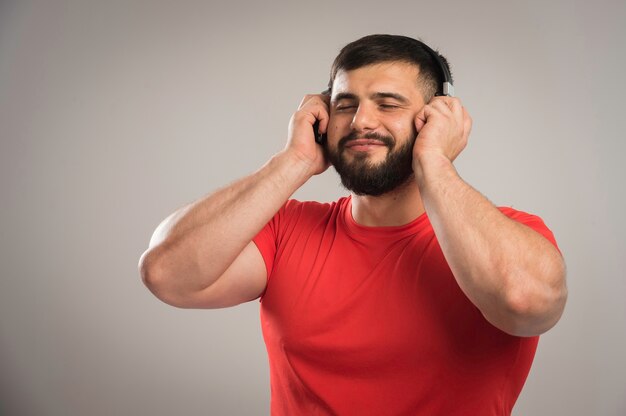 Männlicher DJ im roten Hemd, der Kopfhörer trägt und Musik hört.