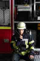 Kostenloses Foto männlicher feuerwehrmann am bahnhof mit anzug und schutzhelm