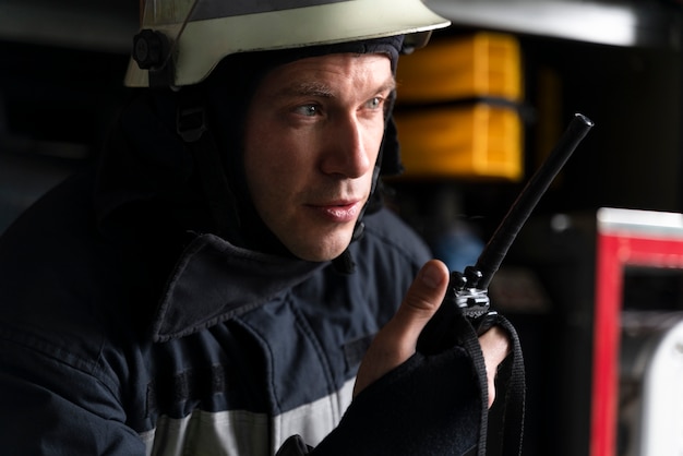 Kostenloses Foto männlicher feuerwehrmann am bahnhof mit anzug und schutzhelm