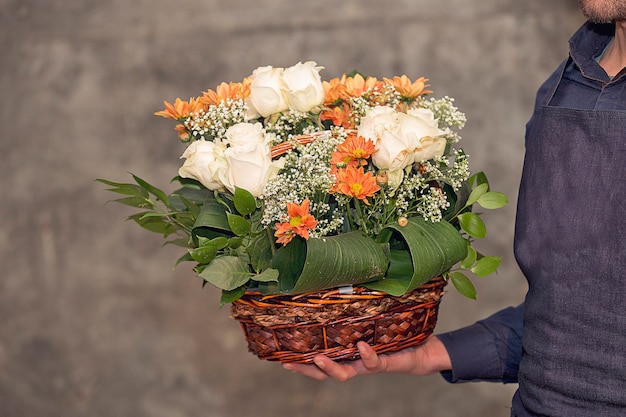 Männlicher Florist, der einen Blumenblumenstrauß innerhalb des Korbes fördert.