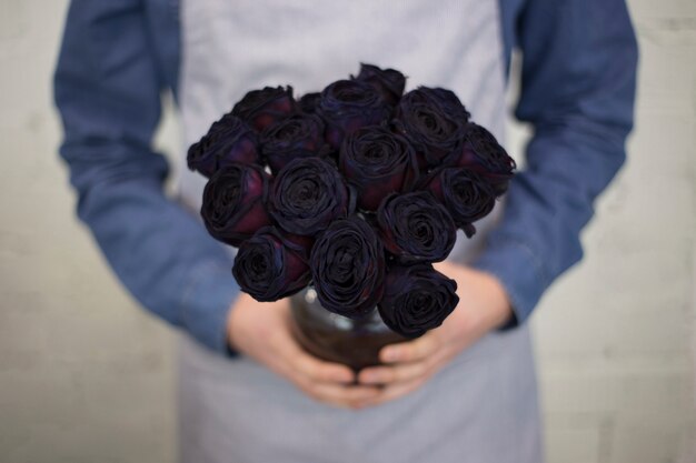 Kostenloses Foto männlicher florist im schutzblech, das in der hand helle farbe hält, stieg blumenstrauß