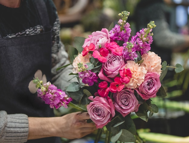 Männlicher Florist makinf ein bunter Blumenblumenstrauß