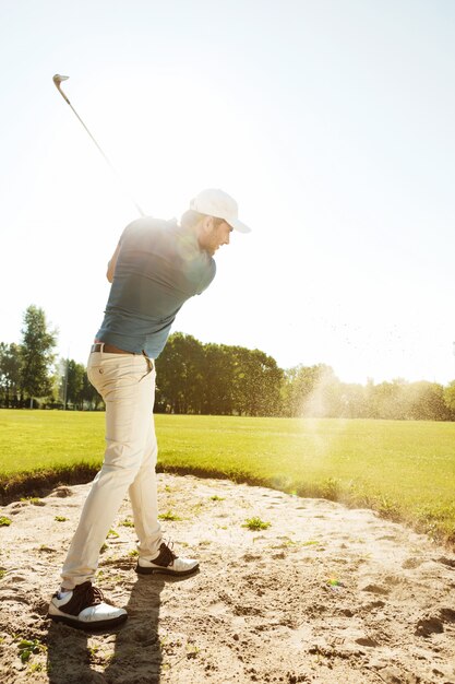 Männlicher Golfer, der Ball aus einem Sandfang schlägt