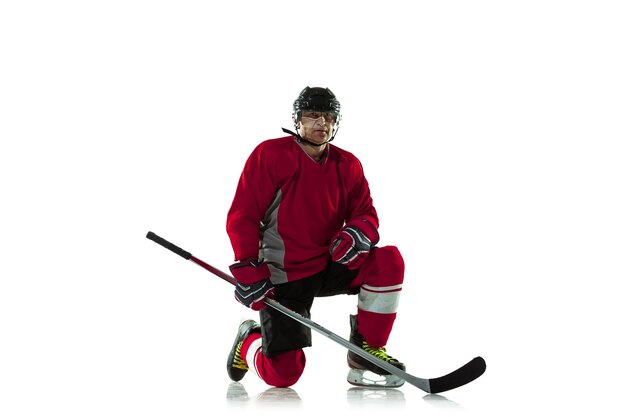 Männlicher Hockeyspieler mit dem Stock auf Eisplatz und weißem Hintergrund.