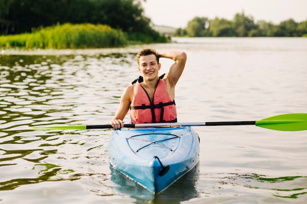 Kostenloses Foto männlicher kayaker, der auf kajak über dem idyllischen see schwimmt