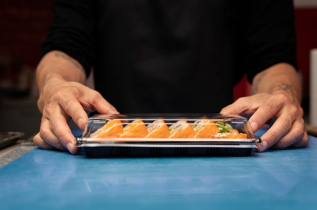 Männlicher Koch bereitet eine Sushi-Bestellung zum Mitnehmen vor