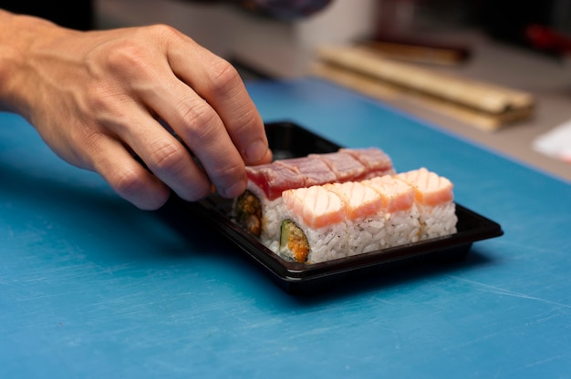 Männlicher Koch bereitet eine Sushi-Bestellung zum Mitnehmen vor