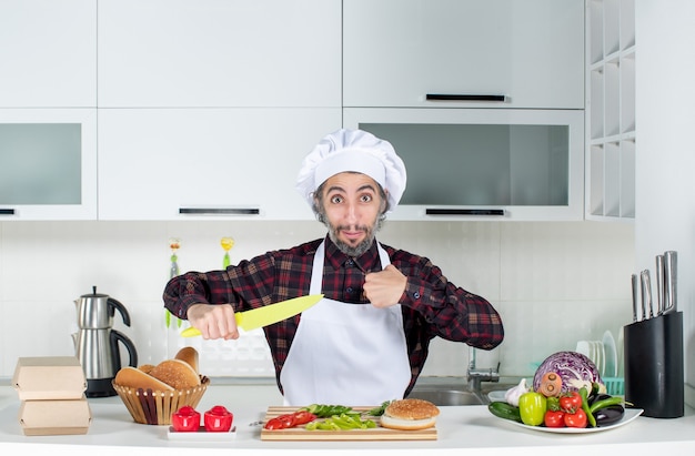 Männlicher Koch der Vorderansicht, der Messer in der Küche hält