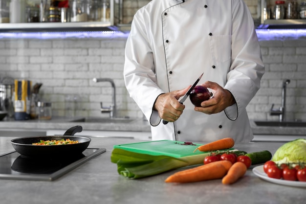 Kostenloses Foto männlicher koch in der küche, der gemüse für gericht hackt
