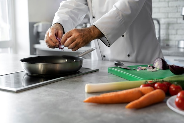 Männlicher Koch in der Küche, der Teller in einer Bratpfanne kocht