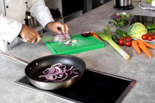 Kostenloses Foto männlicher koch in der küche, der teller in einer bratpfanne kocht