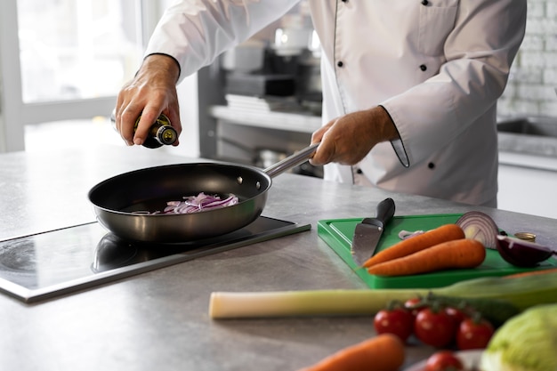 Männlicher Koch in der Küche, der Teller in einer Bratpfanne kocht