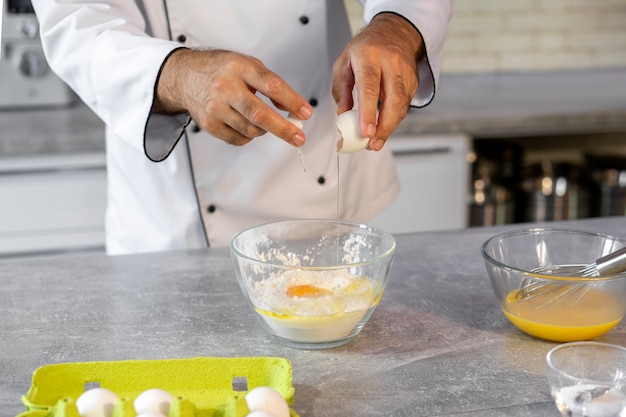 Kostenloses Foto männlicher koch in der küche mit eiern zum kochen