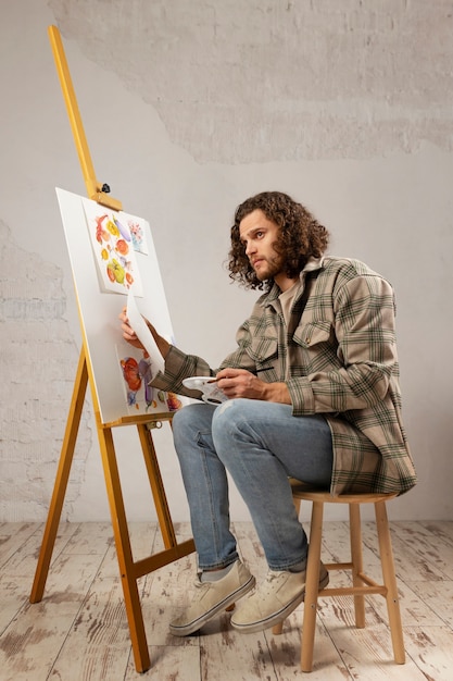 Männlicher Künstler, der im Studio mit Aquarellen malt