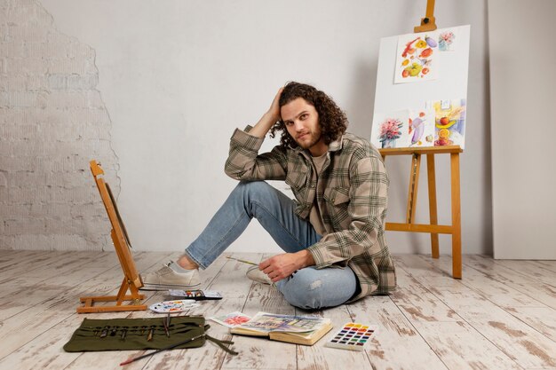 Männlicher Künstler, der im Studio mit Aquarellen malt