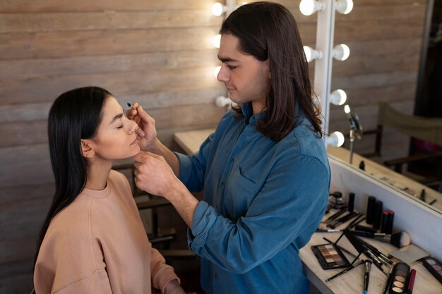 Männlicher Make-up-Künstler, der weibliche Kunden schminkt