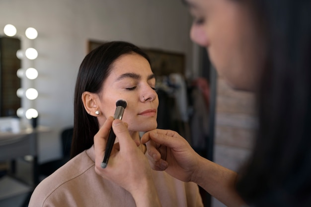 Männlicher Make-up-Künstler, der weibliche Kunden schminkt