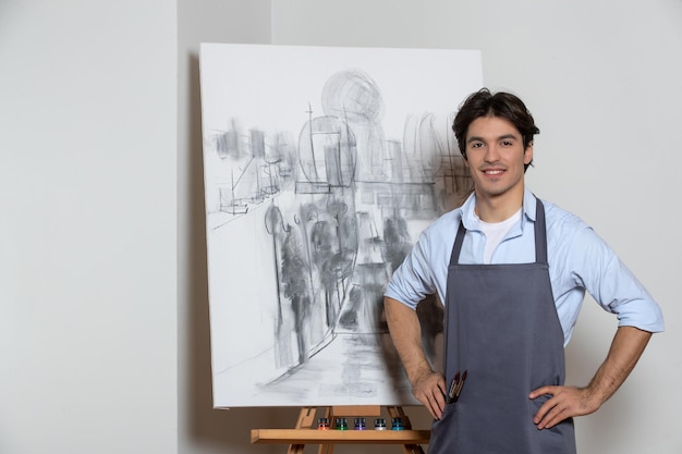 Männlicher maler, der mit seiner schönen weißen hintergrundzeichnung der malerei aufwirft Kostenlose Fotos