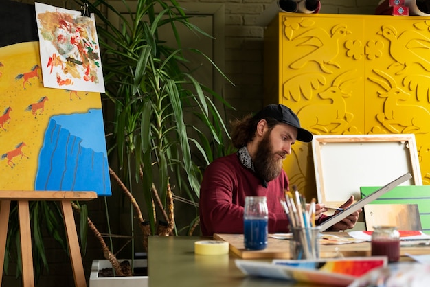 Männlicher Maler im Studio, der Aquarell auf seiner Kunst verwendet