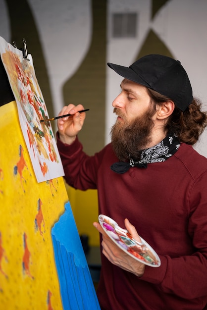 Kostenloses Foto männlicher maler im studio, der aquarell auf seiner kunst verwendet