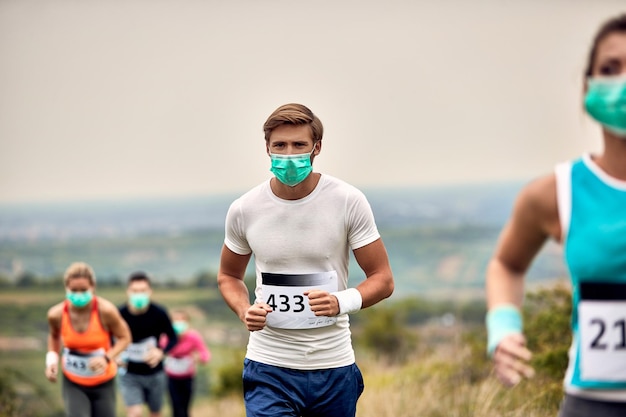 Männlicher Marathonläufer, der eine schützende Gesichtsmaske trägt, während er an einem Rennen während einer Virusepidemie teilnimmt