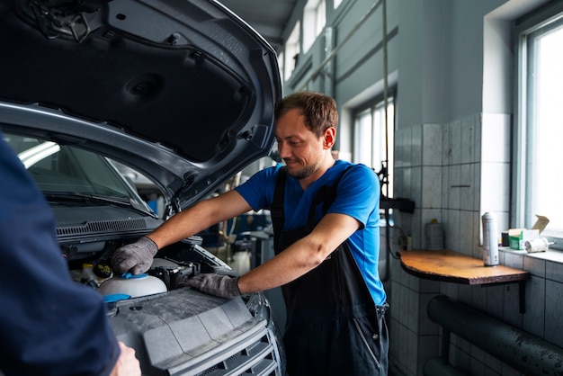 Männlicher Mechaniker, der in der Autowerkstatt am Auto arbeitet