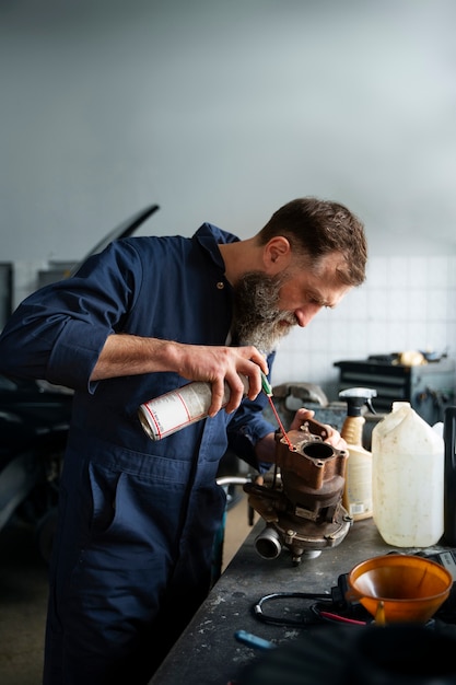 Männlicher Mechaniker, der in der Autowerkstatt am Auto arbeitet