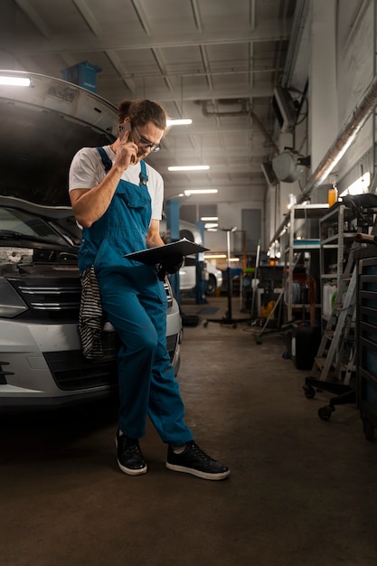 Kostenloses Foto männlicher mechaniker, der in der werkstatt an einem auto arbeitet