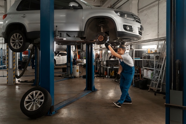 Männlicher Mechaniker, der in der Werkstatt an einem Auto arbeitet