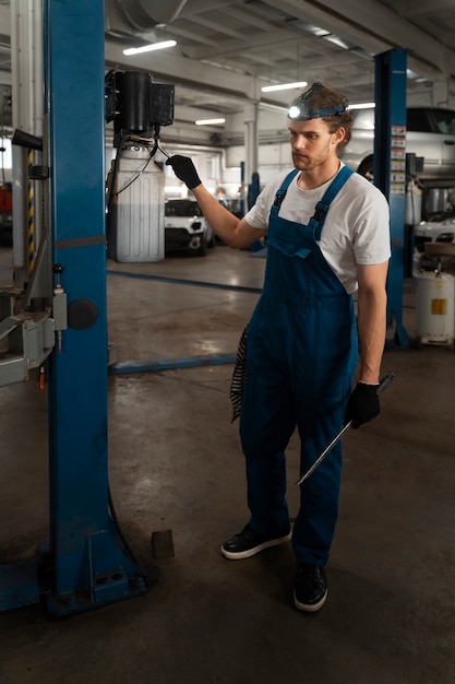 Kostenloses Foto männlicher mechaniker, der in der werkstatt an einem auto arbeitet