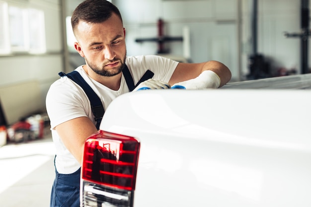 Männlicher Mechaniker der Seitenansicht, der Rückseite des Autos überprüft