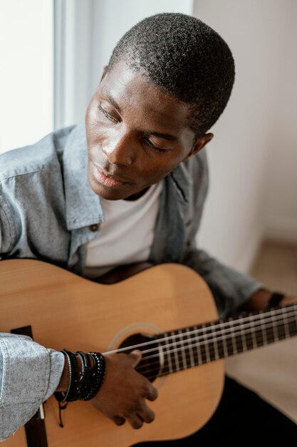 Männlicher Musiker, der Gitarre auf Bett spielt