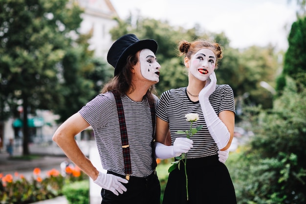 Männlicher Pantomime, der glücklichen weiblichen Pantomimen im Park betrachtet