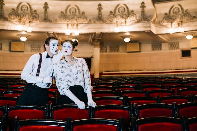 Kostenloses Foto männlicher pantomime, der im ohr des weiblichen pantomimen im auditorium flüstert