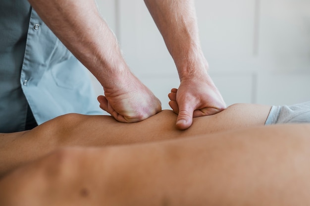 Männlicher Physiotherapeut auf einer Massagesitzung mit Patientin