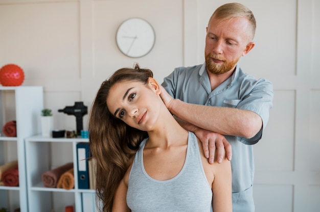 Männlicher Physiotherapeut, der Behandlungsübungen mit weiblichem Patienten durchführt