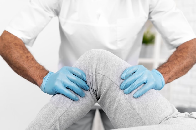 Männlicher physiotherapeut, der die kniemobilität der frau überprüft