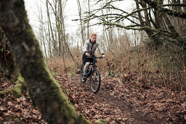Männlicher Radfahrer, der Mountainbike im Wald reitet