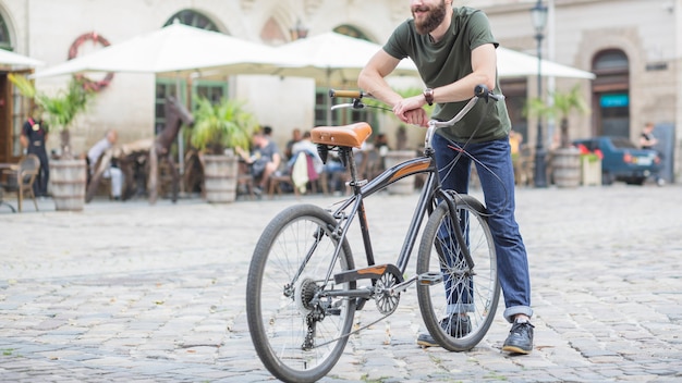 Männlicher Radfahrer mit dem Fahrrad, das auf Stadtstraße steht